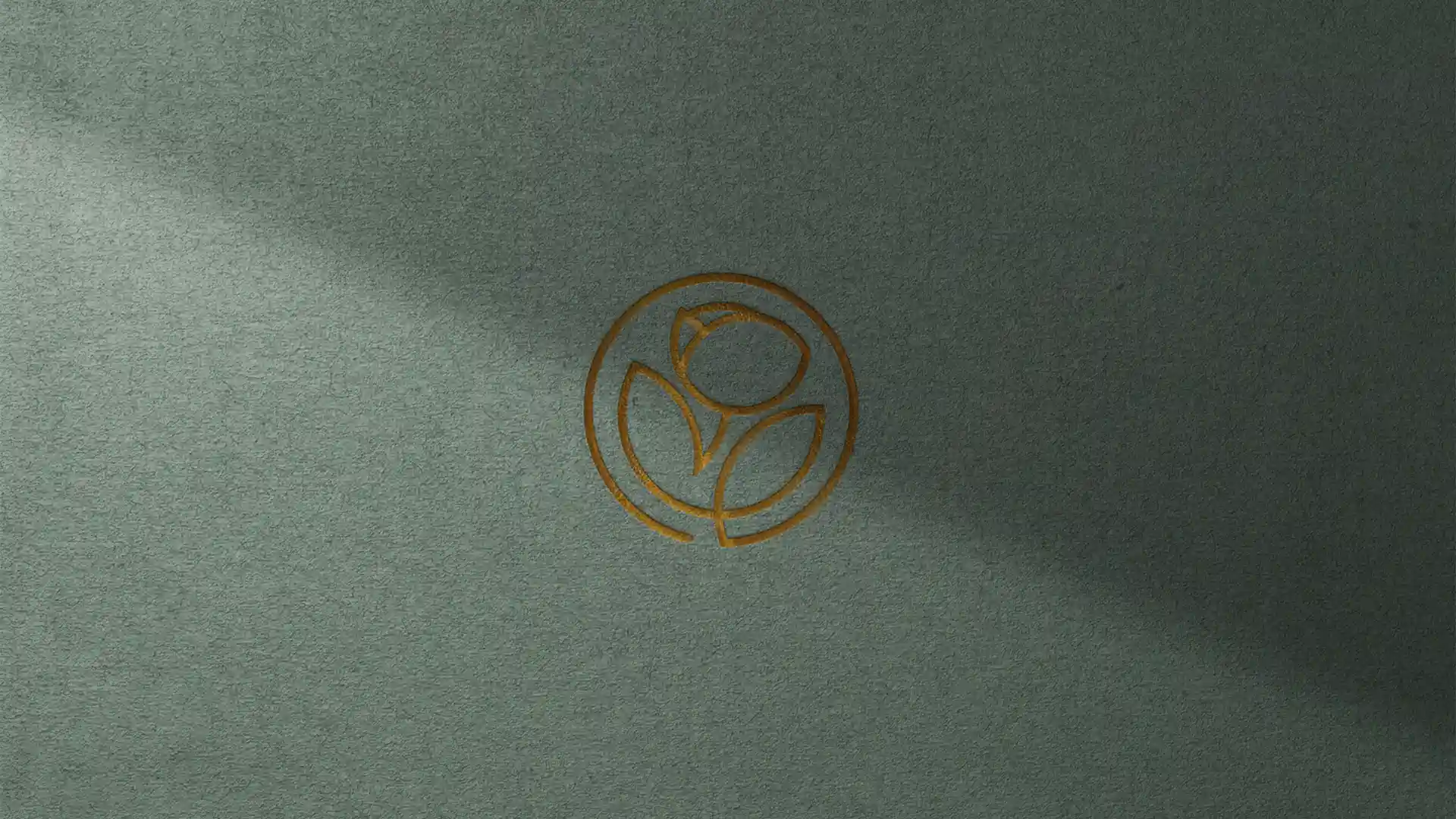 Un logo dorée gravé sur un fond vert. Le logo est linaire en un seul trait et représente une fleur. C'est un joli logo moderne et épuré. L'image sert à illustrer l'article qui explique pourquoi je recycle mes logos